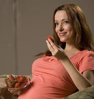 Mujer embarazada comiendo fresas.
