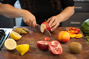 Mujer que corta frutas en una tabla de picar.