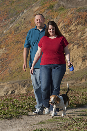 Un hombre y una mujer al aire libre paseando el perro.