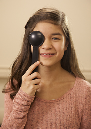 Una niña sosteniendo un cobertor sobre el ojo durante un examen de la vista.
