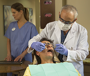 Proveedores de atención médica dental examinan los dientes de una mujer.